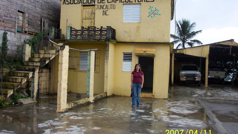 Katherine Devine stands in front of a building reading "Associacion de Caficultores"