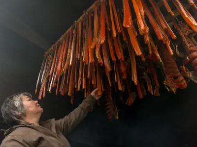 Kim Williams looks up to inspect strips of salmon inside her Bristol Bay smokehouse