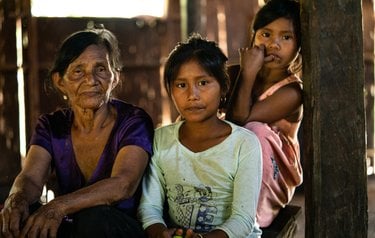 A color photo portrait of a grandmother and two of her granddaughters looking into the camera