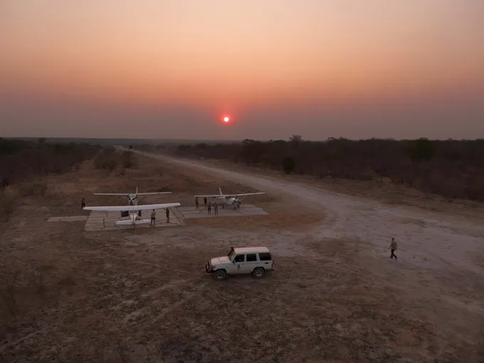 Landing field in savanna landscape with 2 planes at sunset