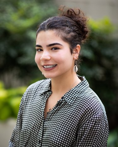 A professional photo of a woman wearing a black and white checkered top with her hair up.
