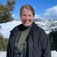 Leigh Henry standing in front of snowy trees and mountains