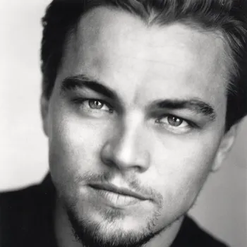 A black and white headshot of a white man and short beard and moustache looking intense at the camera.