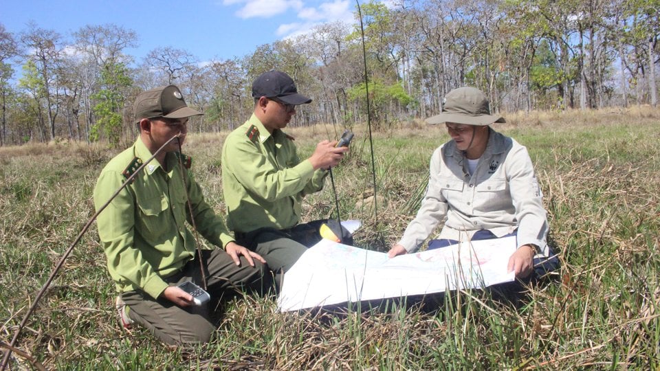 People sit on the ground reviewing a map in a field