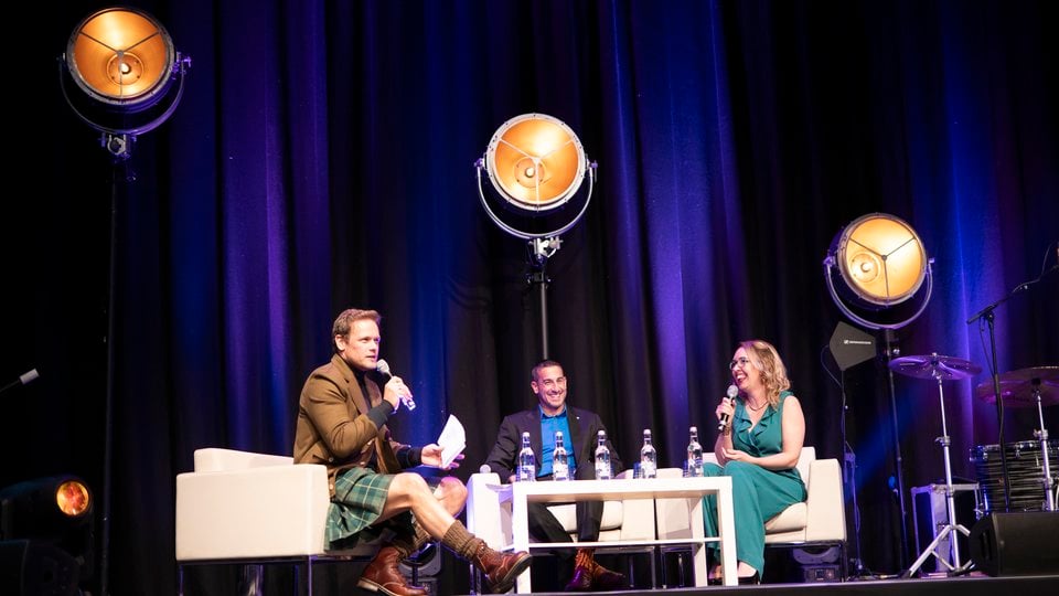 Nikhil Advani, Lyndsey Dodds, and Sam Heughan onstage
