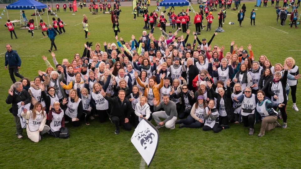 A large group of people wearing team WWF jerseys pose in a sports field.