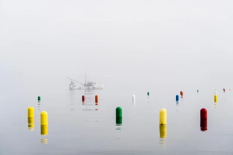 buoys mark seaweed farm off coast of Falmouth, Maine with boat in distance