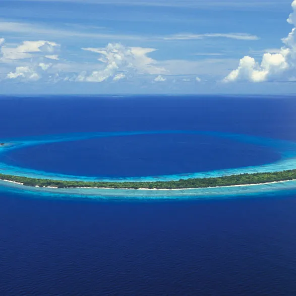 An aerial view of a small crescent shaped island in the ocean.