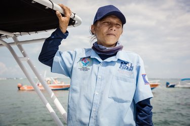 Una persona está de pie cerca del costado de una barca en el agua.
