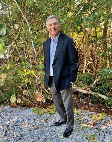 Sanjeev Mehra standing for a headshot with plants in the background