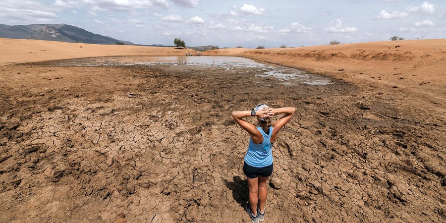 Female runner stands looking at dry watering hole