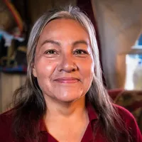 A portrait of Monica Rattling Hawk smiling into the camera in 2020