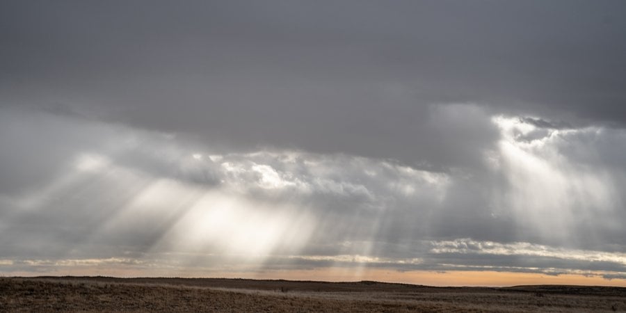 sun breaks through clouds over grasslands in Montana