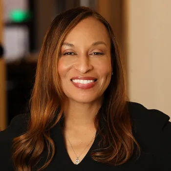 Headshot of A Black woman with long brown hair, wearing a black shirt.
