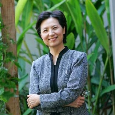 A woman smiles in front of tall plants