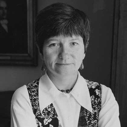 A black and white portrait photo of a woman with short hair and a white shirt with pointy collars