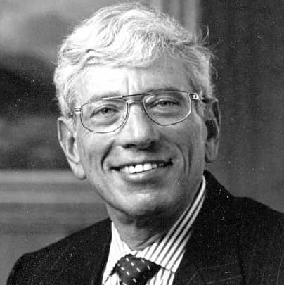 A black and white headshot of a smiling older man