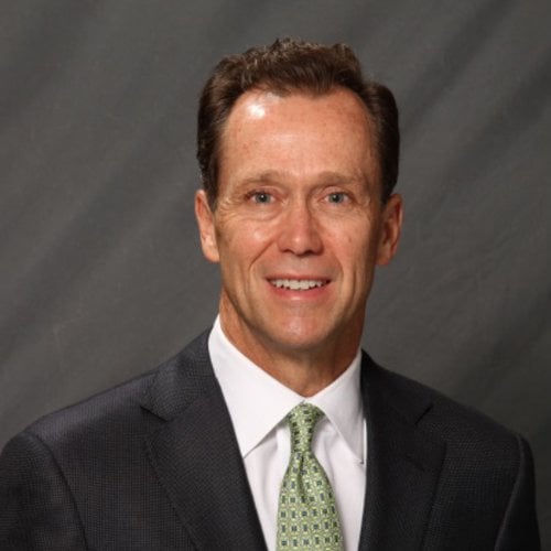 Gregory L. Summe smiles at the camera, wearing a suit and against a gray background