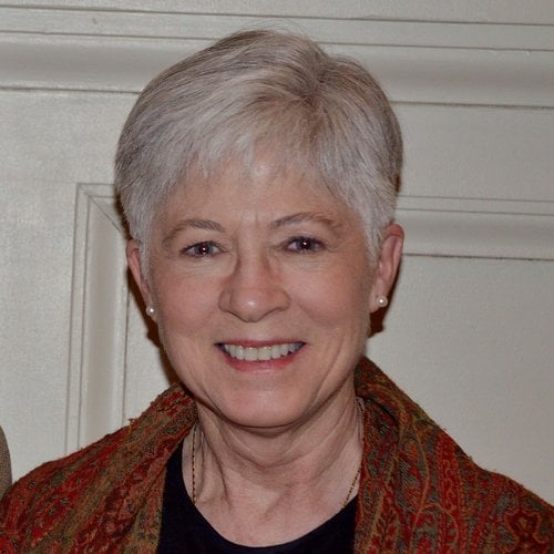 Karen W. Wagoner smiles at the camera with a red scarf draped around her shoulders