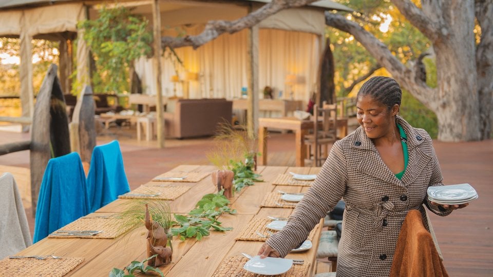 Catherine Mafumelo sets plates on an outdoor table
