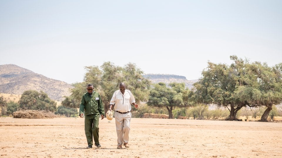 Two men walking toward camera in dry landscape