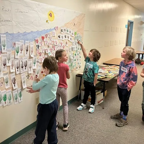5 elementary school children look at a mural titled "Maine's Rocky Intertidal Seaweed"