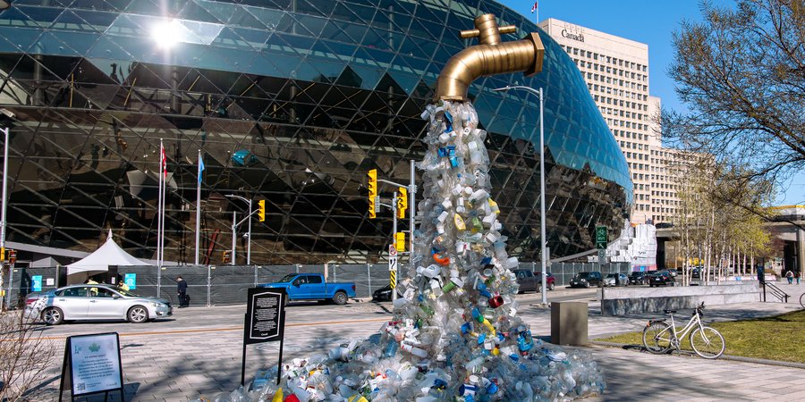 A sculpture of plastic bottles is shaped like a tap and stands in front of the building where negotiations on an international plastic treaty took place