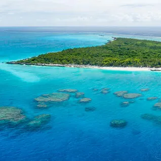 Panoramic view of an islet surrounded by ocean and shallow reefs