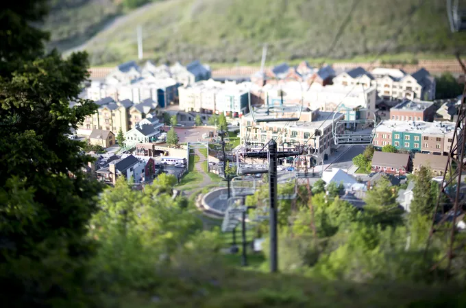 Houses and a ski lift set in a green forested area.