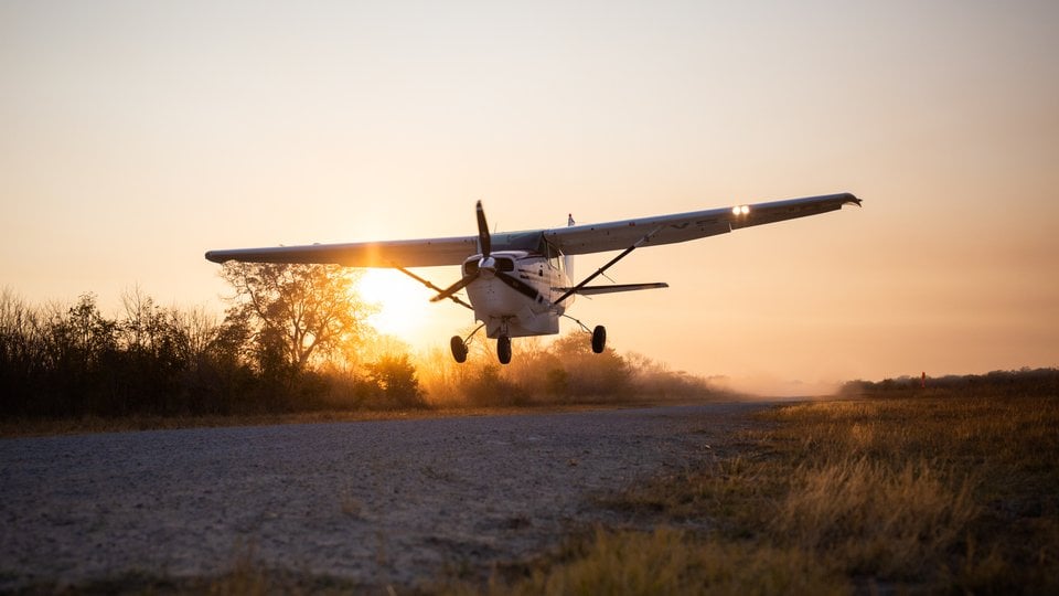 A small plane taking off at sunrise