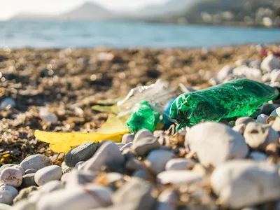A green plastic bottle on a rocky beach