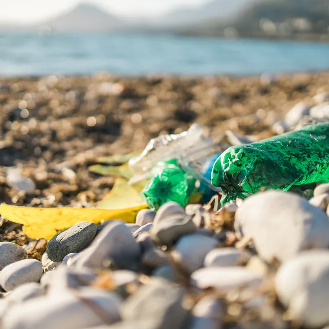 A green plastic bottle on a rocky beach
