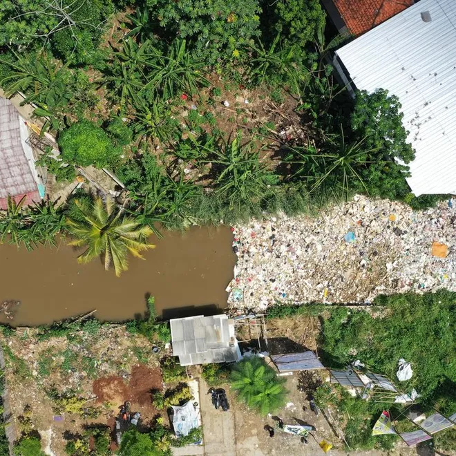 Aerial view of plastics clogging a river between homes in Indonesia