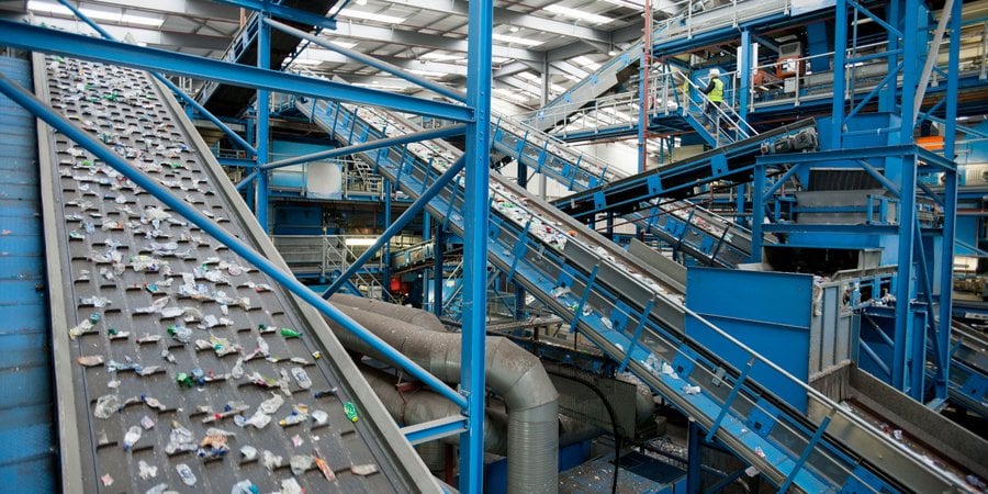 A series of blue and gray conveyor belts moves plastics along at a recycling plant