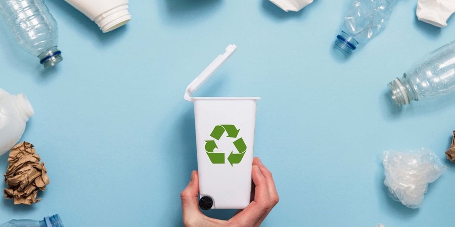 A semi circle of plastics surround a tiny recycling bin on a blue background