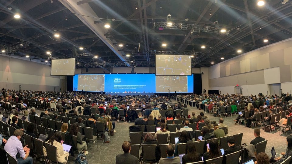 A view of an auditorium full of people with a screen at the front