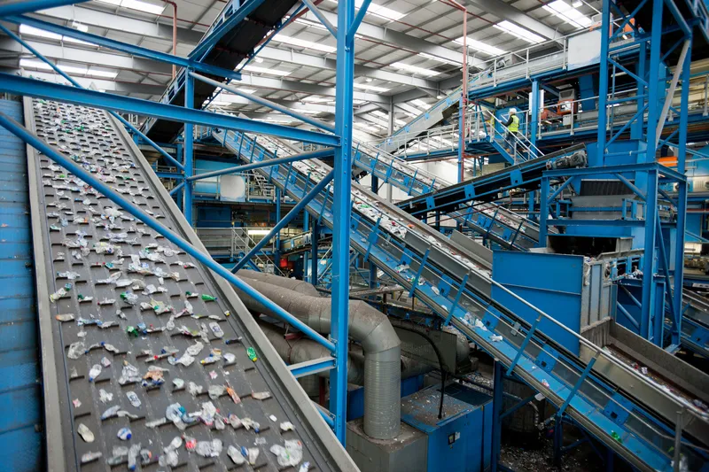 A series of blue and gray conveyor belts moves plastics along at a recycling plant