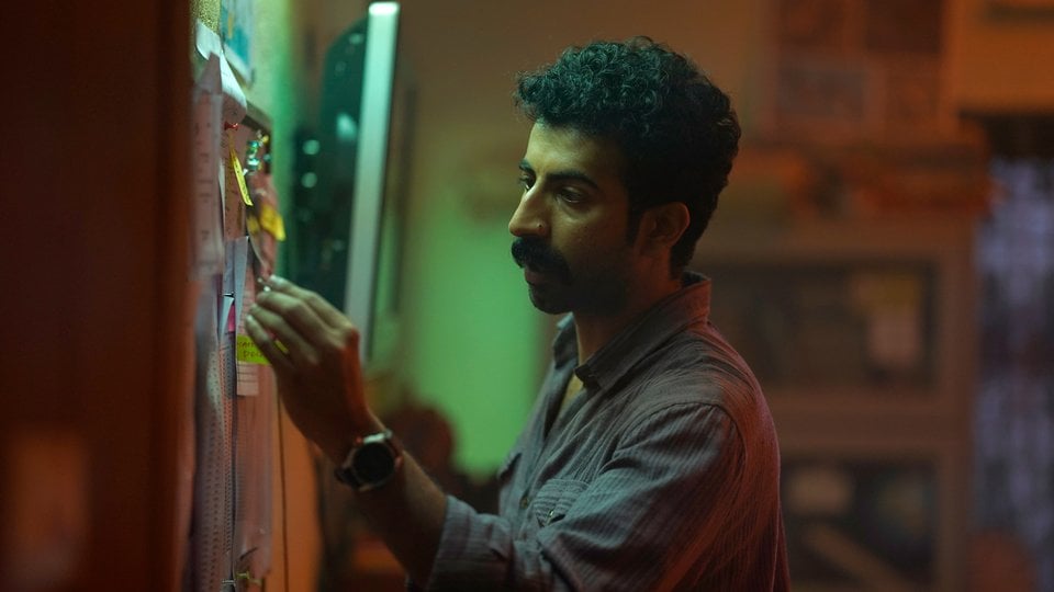 Actor Roshan Matthew arranges evidence on a wall in a still from the series Poachers