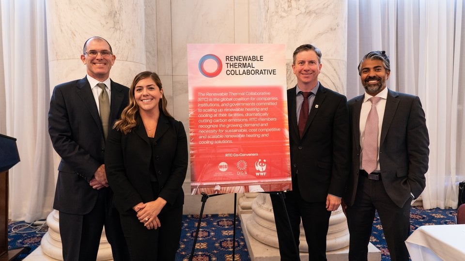 Four people stand with a "Renewable Thermal Collaborative" sign