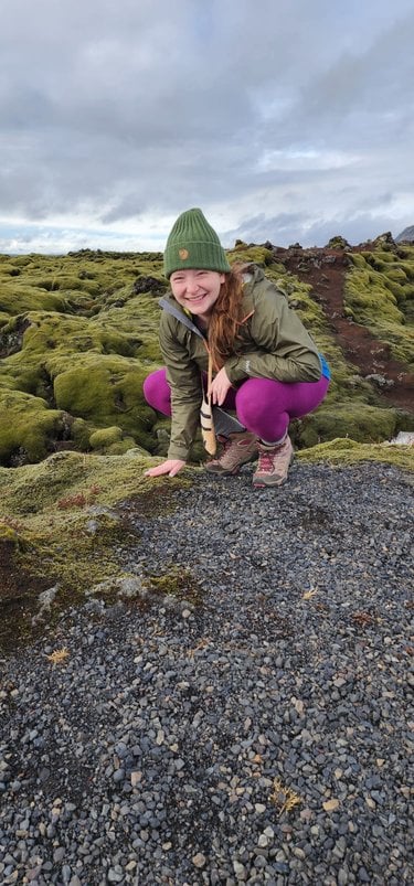 Rachel Golden Kroner crouches before a mossy landscape