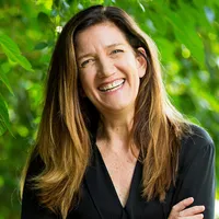 Rachel Shaw smiles warmly. She is a white woman with long brown hair and is wearing a black shirt.