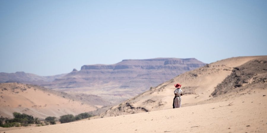 Rebecca Adams, a goat herder, stands in the stark landscape outside De Riet village, Namibia