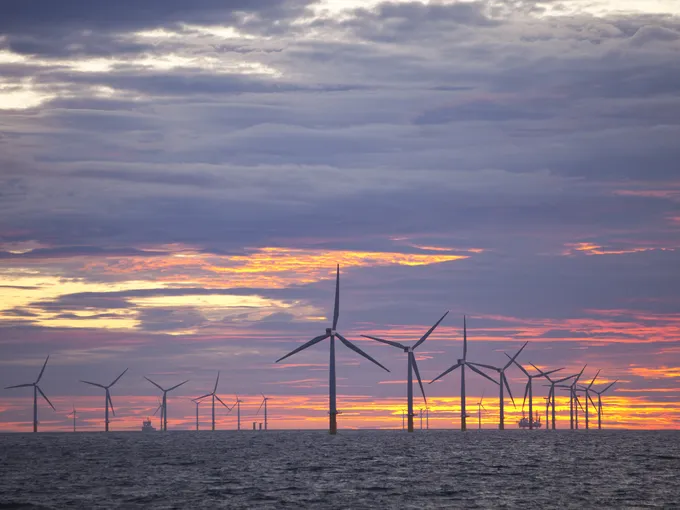 Two lines of offshore windmills farm at sunset.