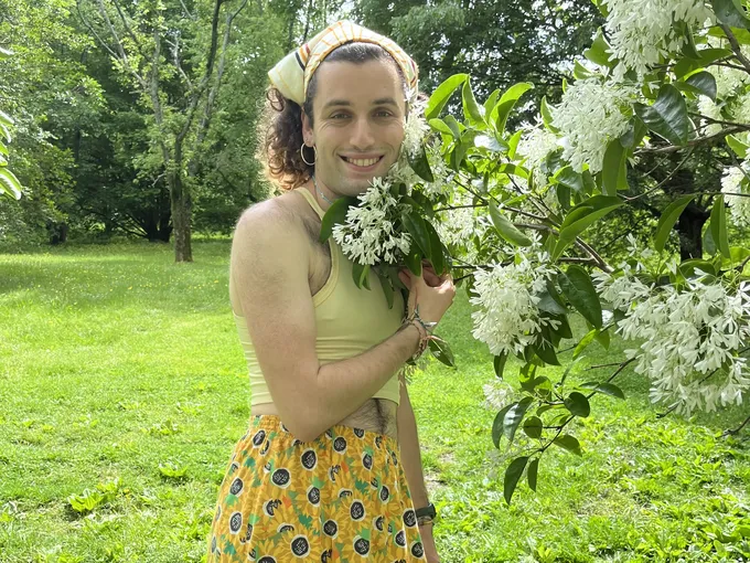 A person stands next to flowers.