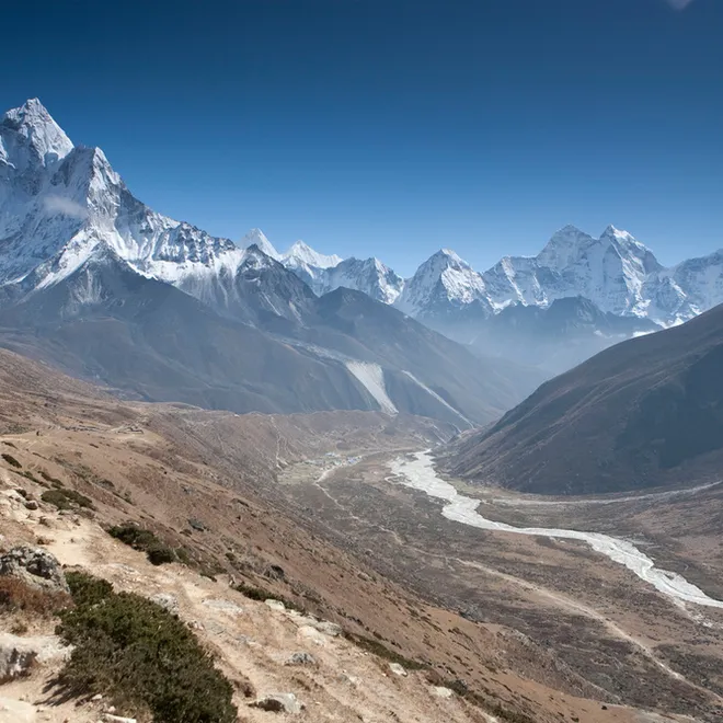 Landscape view of a river in a deep valley with snowcapped mountains in the background