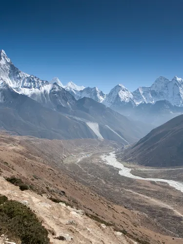 Landscape view of a river in a deep valley with snowcapped mountains in the background