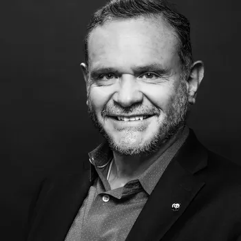 Black and white headshot of Roberto Troya wearing a blazer