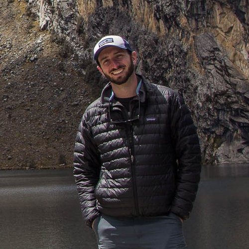 Ryan Bartlett standing in front of water with a rocky hill in the background
