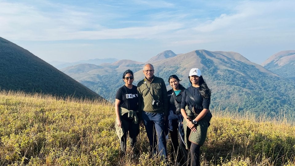 Four people stand in a field with mountains in the background