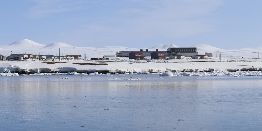 A snow land meets sea, with a few houses